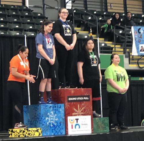 Students stand on the awards podium for Girls Eskimo Stick Pull. 